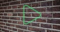 Composite of illuminated digital green play button icon against brick wall, copy space