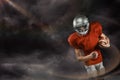 Composite image of american football player in red jersey looking down while holding ball Royalty Free Stock Photo