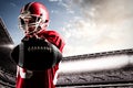 Composite image of american football player standing in rugby helmet and holding rugby ball Royalty Free Stock Photo