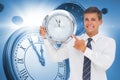 Composite image of anxious businessman holding and showing a clock