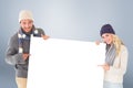 Composite image of attractive couple in winter fashion showing poster Royalty Free Stock Photo