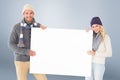 Composite image of attractive couple in winter fashion showing poster Royalty Free Stock Photo