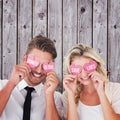 Composite image of attractive young couple holding pink hearts over eyes Royalty Free Stock Photo