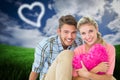 Composite image of attractive young couple sitting holding heart cushion Royalty Free Stock Photo