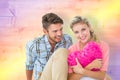 Composite image of attractive young couple sitting holding heart cushion Royalty Free Stock Photo