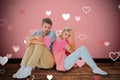 Composite image of attractive young couple sitting holding two halves of broken heart Royalty Free Stock Photo