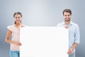 Composite image of attractive young couple smiling at camera holding poster Royalty Free Stock Photo