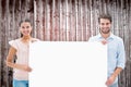 Composite image of attractive young couple smiling at camera holding poster Royalty Free Stock Photo