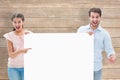 Composite image of attractive young couple smiling at camera holding poster Royalty Free Stock Photo