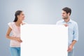 Composite image of attractive young couple smiling and holding poster Royalty Free Stock Photo