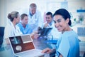 Composite image of beautiful smiling doctor typing on keyboard with her team behind Royalty Free Stock Photo