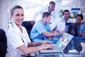 Composite image of beautiful smiling doctor typing on keyboard with her team behind Royalty Free Stock Photo