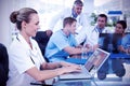 Composite image of beautiful smiling doctor typing on keyboard with her team behind Royalty Free Stock Photo