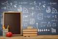 Composite image of books by slate with desk organizer and apple on wooden table Royalty Free Stock Photo