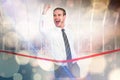 Composite image of businessman crossing the finish line while clenching fist Royalty Free Stock Photo