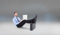 Composite image of businessman sitting on the floor with feet up on suitcase Royalty Free Stock Photo