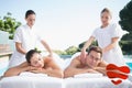 Composite image of calm couple enjoying couples massage poolside Royalty Free Stock Photo