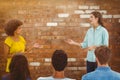 Composite image of casual young businesswoman giving presentation to colleagues Royalty Free Stock Photo