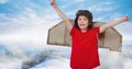 Composite image of caucasian boy in airplane costume against blue sky over winter landscape