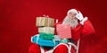 Composite image of cheerful santa claus holding chritmas presents while sitting on chair Royalty Free Stock Photo