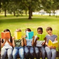 Composite image of children reading books at park Royalty Free Stock Photo