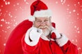 Composite image of close-up portrait of santa claus pointing while carrying christmas bag Royalty Free Stock Photo