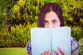 Composite image of close up portrait of woman hiding behind book Royalty Free Stock Photo