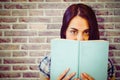 Composite image of close up portrait of woman hiding behind book Royalty Free Stock Photo