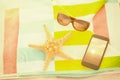 Composite image of close up of starfish with sunglasses and mobile phone kept on beach blanket