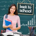 Composite image of college girl holding books with blurred students in park