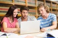 Composite image of college students using laptop in library Royalty Free Stock Photo