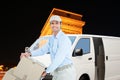 Composite image of confident delivery man pushing trolley of cardboard boxes Royalty Free Stock Photo