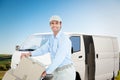 Composite image of confident delivery man pushing trolley of cardboard boxes Royalty Free Stock Photo