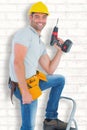 Composite image of confident handyman holding power drill while climbing ladder Royalty Free Stock Photo