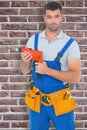 Composite image of confident male carpenter in overall holding drill machine Royalty Free Stock Photo