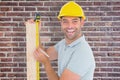 Composite image of construction worker using measure tape to mark on plank Royalty Free Stock Photo