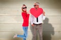 Composite image of cool couple holding a red heart together