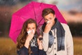 Composite image of couple blowing nose while holding umbrella