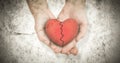 Composite image of couple holding broken heart in hands