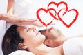 Composite image of a couple receiving a massage with love hearts