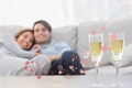 Composite image of couple resting on a couch with flutes of champagne Royalty Free Stock Photo
