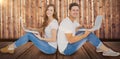 Composite image of couple sitting on floor back to back using laptop Royalty Free Stock Photo