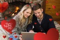 Composite image of couple using laptop in front of lit fireplace