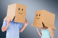 Composite image of couple wearing emoticon face boxes on their heads