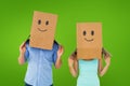 Composite image of couple wearing emoticon face boxes on their heads