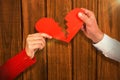 Composite image of cropped hands of couple holding cracked red heart shape