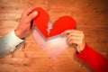 Composite image of cropped hands of couple holding cracked red heart shape