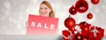 Composite image of cute blonde showing a red sale poster Royalty Free Stock Photo