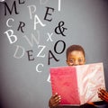 Composite image of cute boy reading book in library Royalty Free Stock Photo