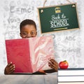 Composite image of cute boy reading book in library Royalty Free Stock Photo